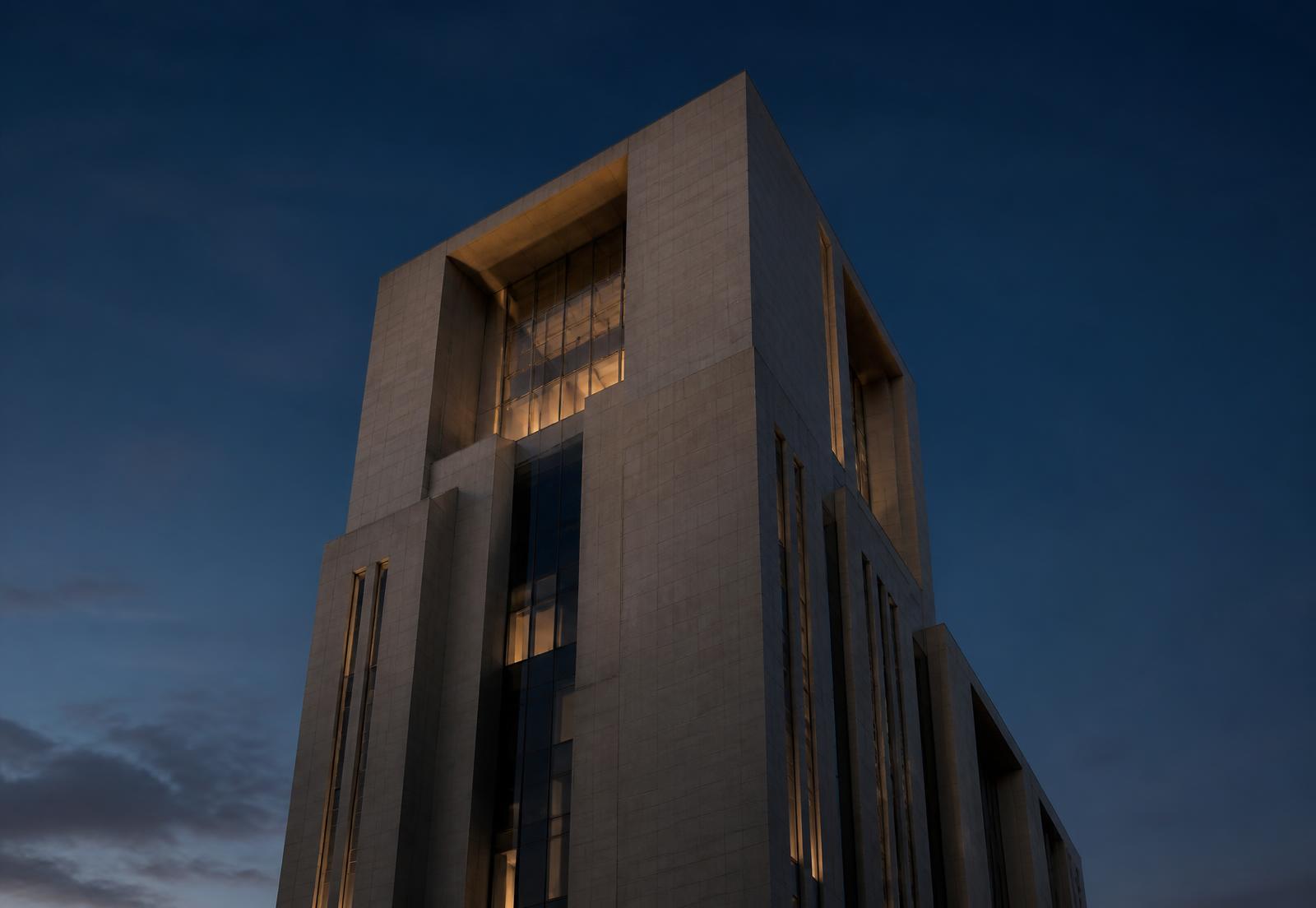 Limestone and glass office tower at dusk
